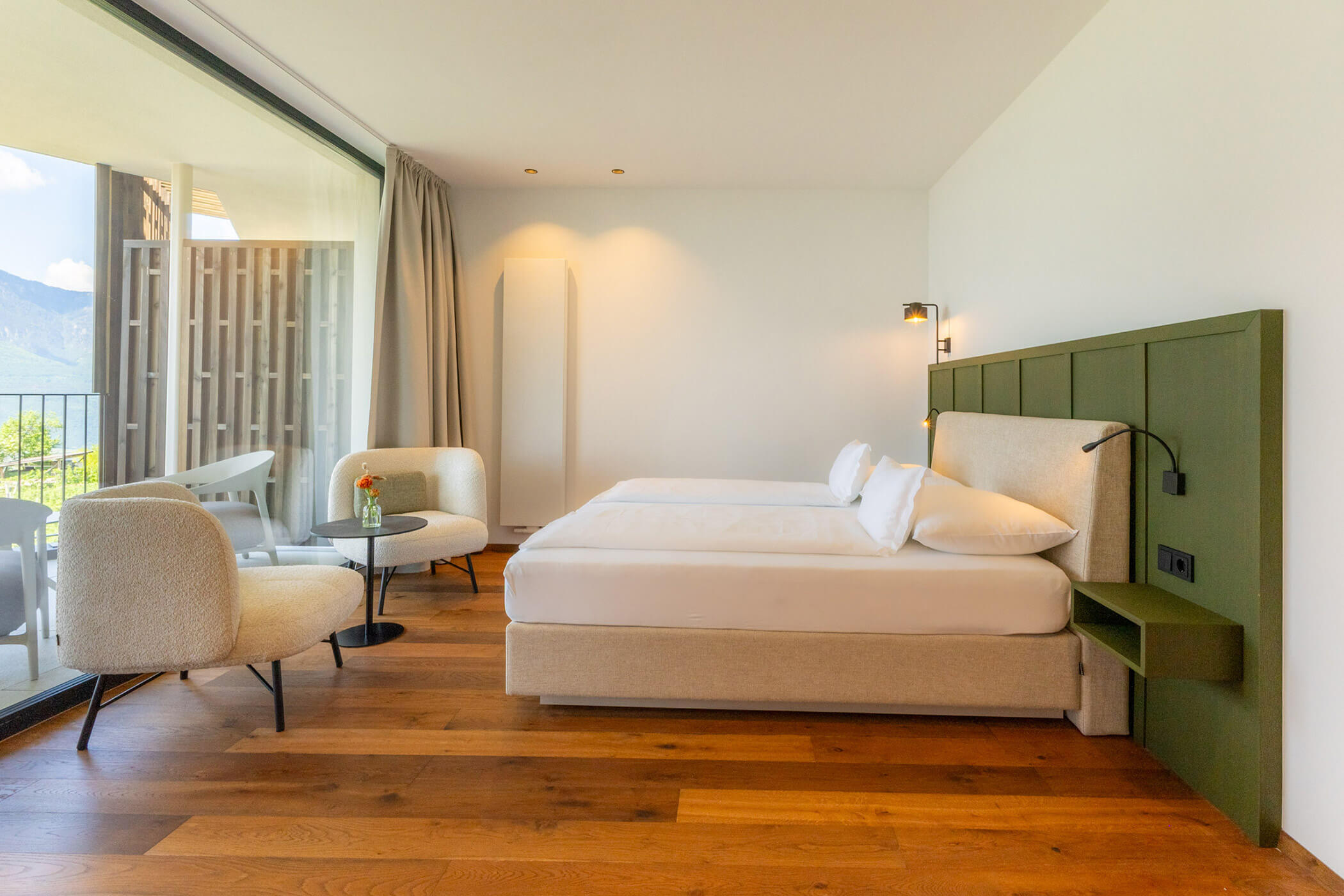 Modern hotel room with a double bed, two chairs, small table, wood floor, and balcony view. - Hotel Tenz