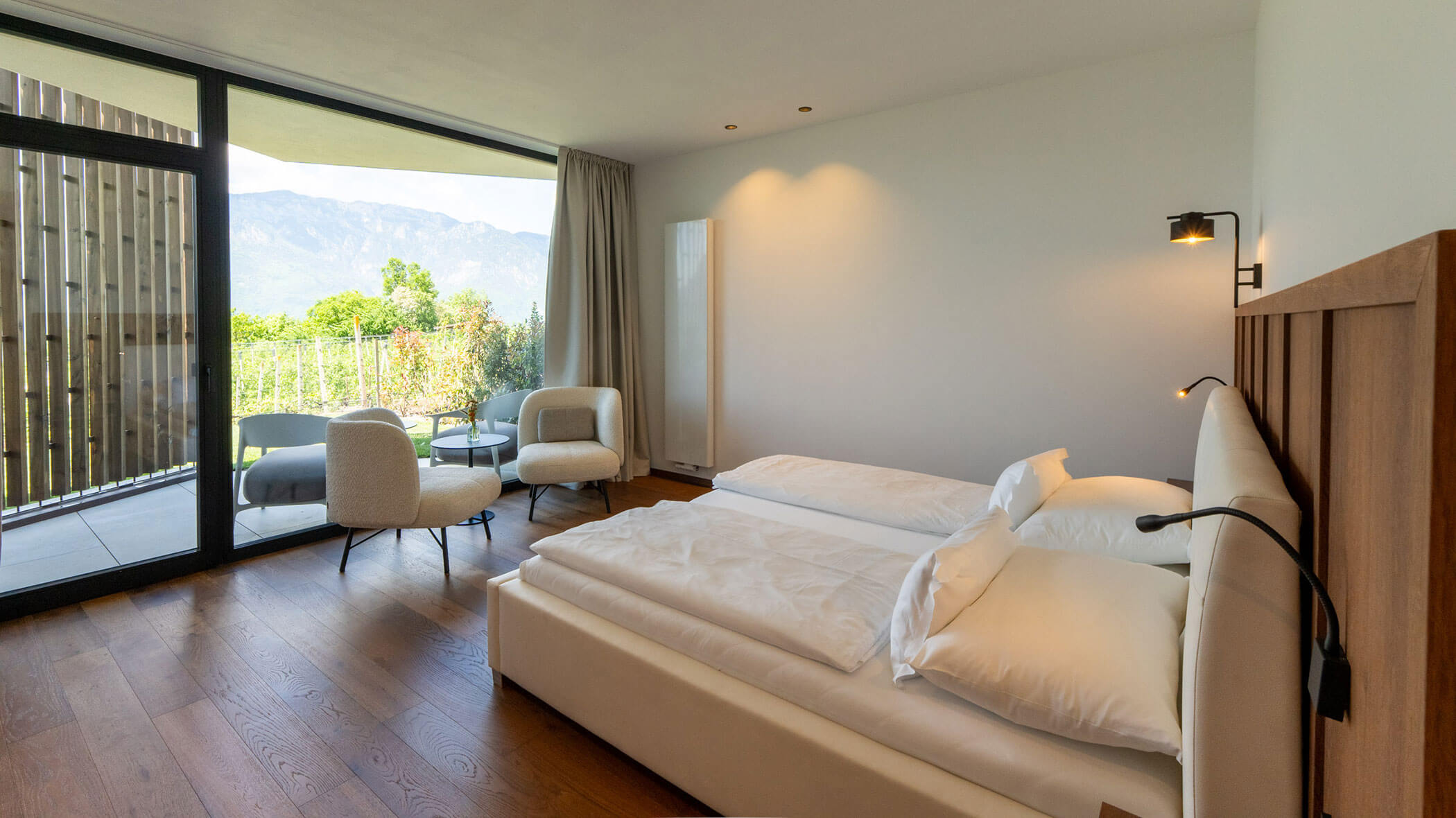 Modernes Hotelzimmer mit Doppelbett, Stühlen, großem Fenster und Blick auf die Berge. - Hotel Tenz