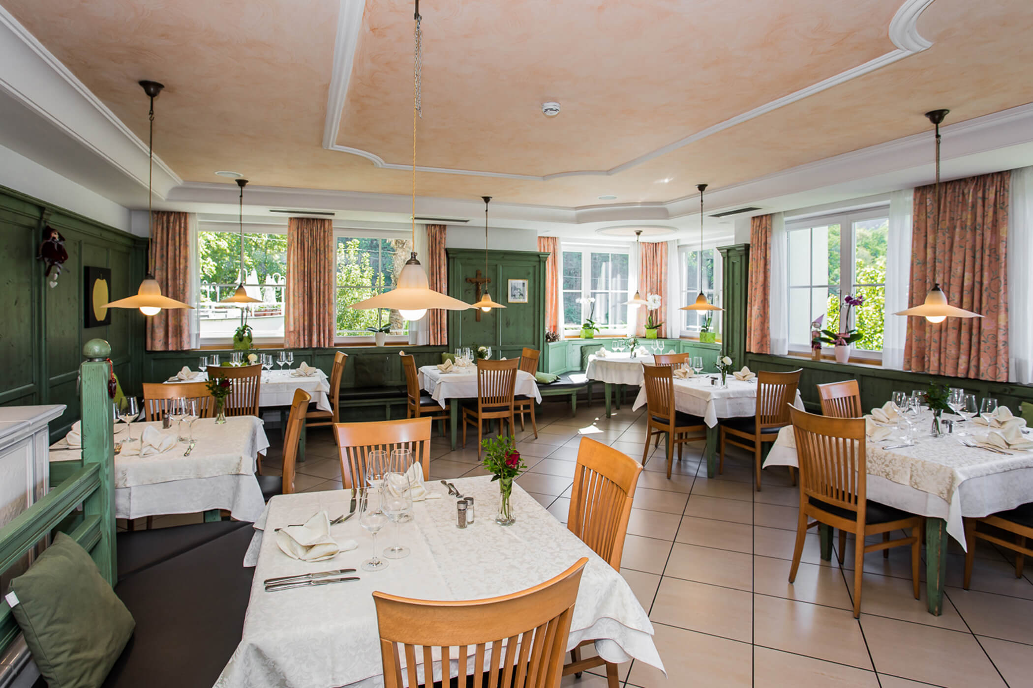 Bright, elegant restaurant dining room with set tables, wooden chairs, and large windows letting in natural light. - Hotel Tenz